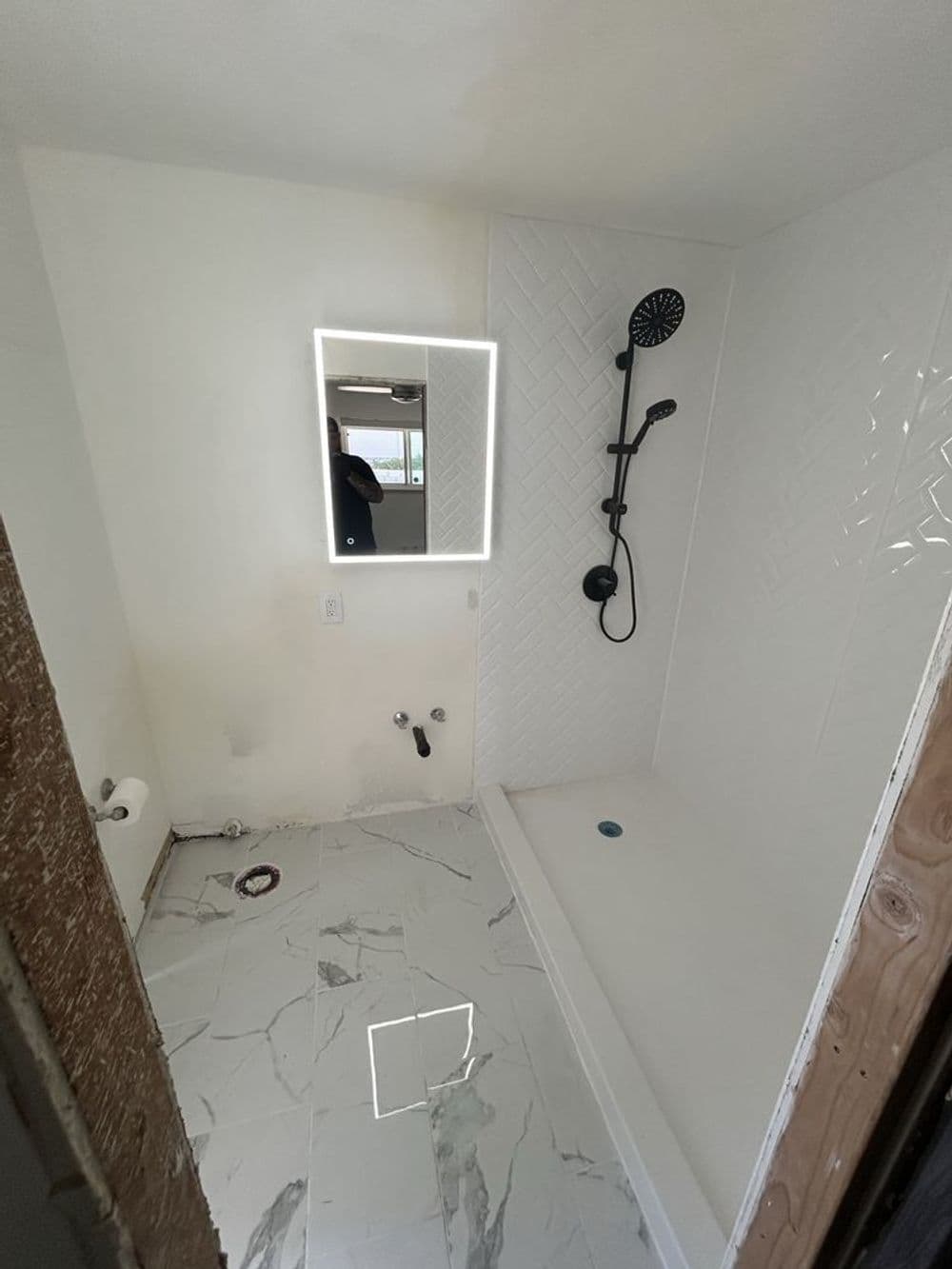 Modern bathroom with a shower, sleek mirror, and marble tile flooring.