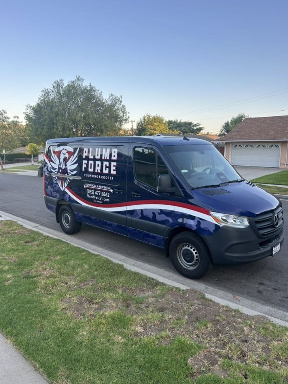 Plumb Force plumbing service van parked on a suburban street.