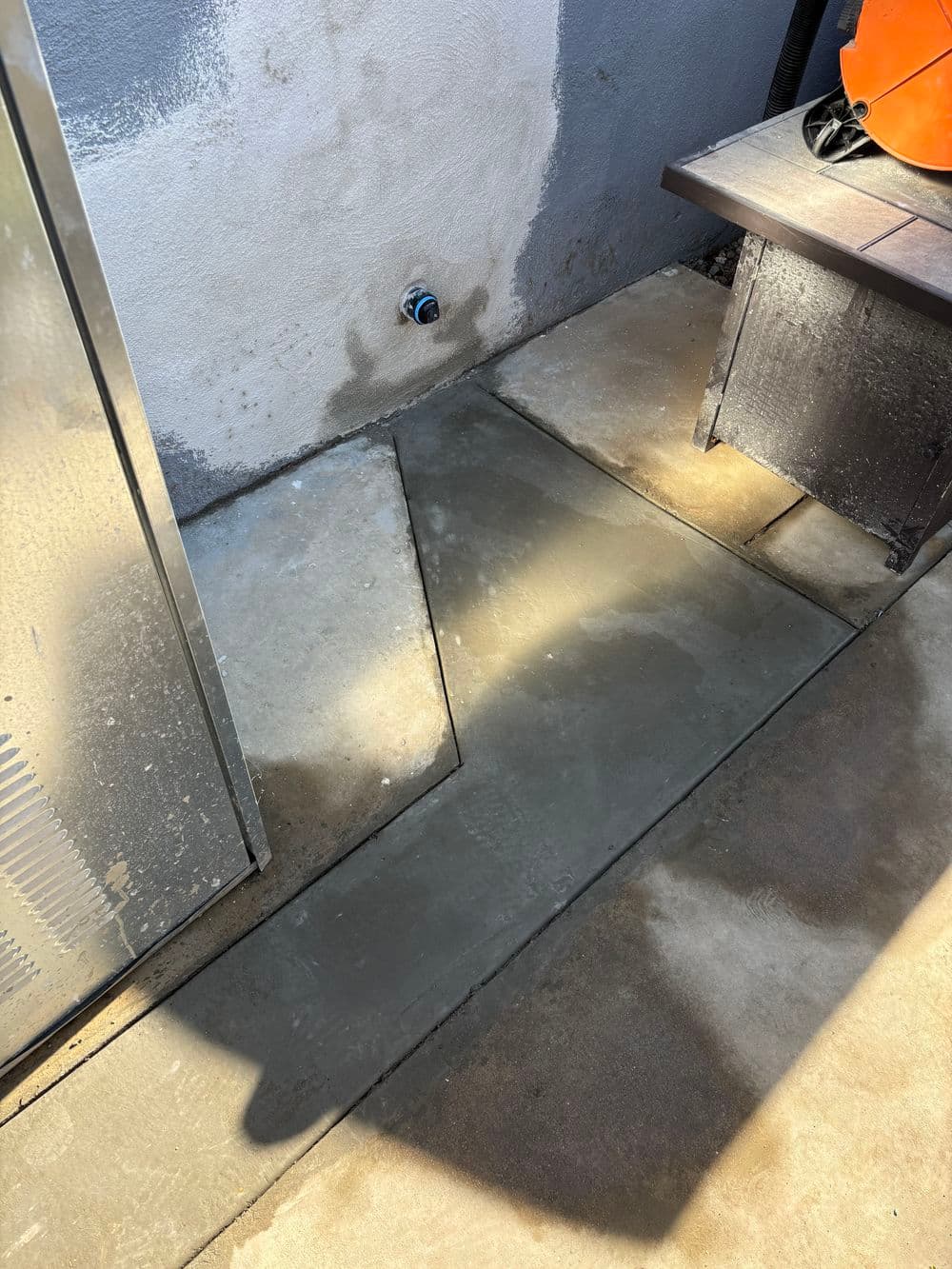Concrete walkway installation with a water access point and outdoor setting.
